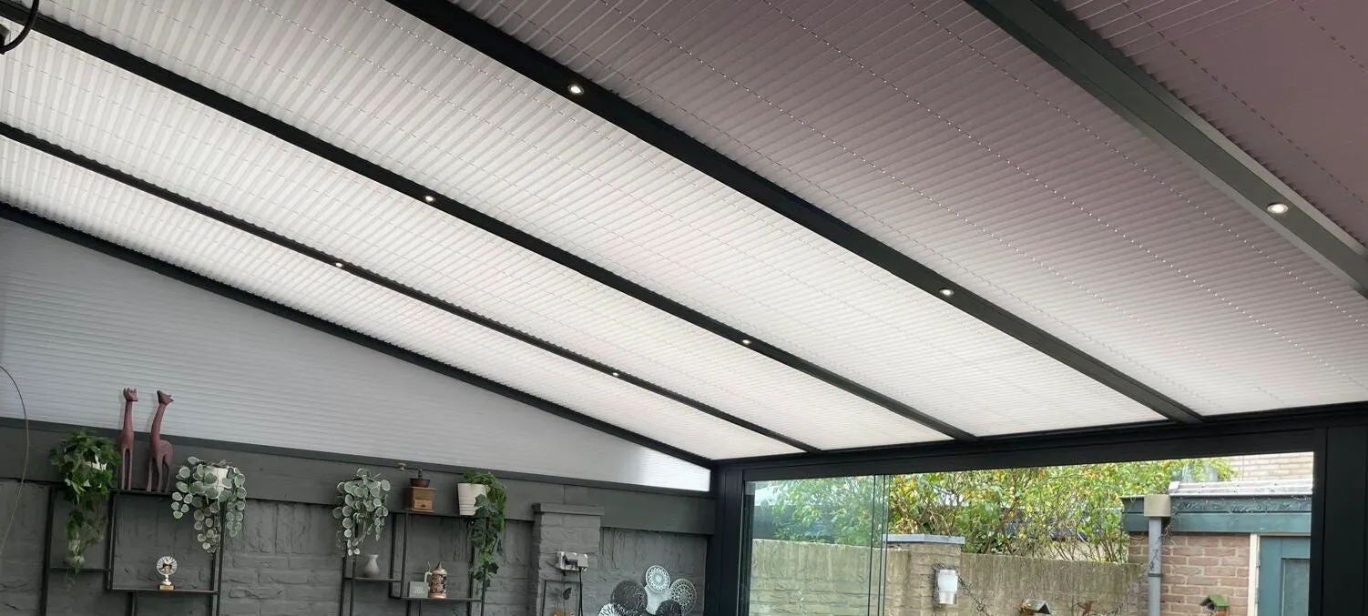 Veranda van binnen gezien, met lichte dakplaten en planten tegen de achterwand