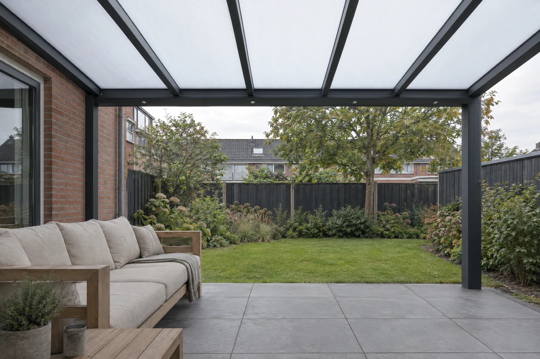 Zicht vanonder een antraciet veranda met polycarbonaat dak, uitkijkend op de tuin